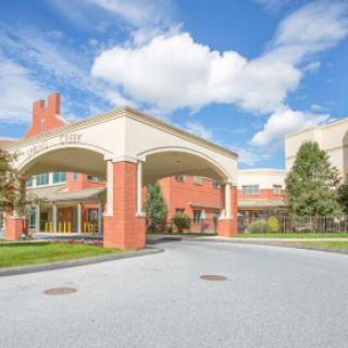 A welcoming entrance of a building under a blue sky with fluffy clouds.