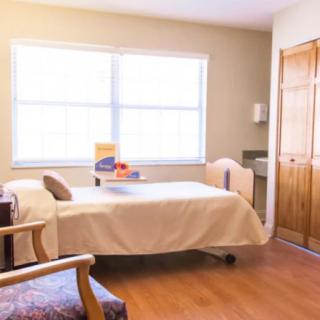 A bright and simple bedroom with a bed, chair, and wardrobe.