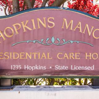 A sign for Hopkins Manor Residential Care Home, indicating it is a state-licensed facility.