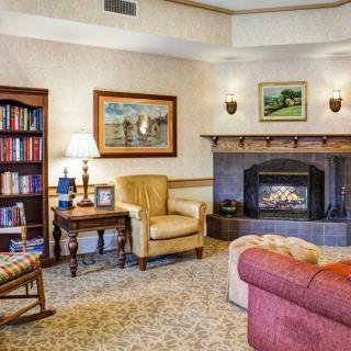A cozy living room with a fireplace, armchair, and bookshelf.