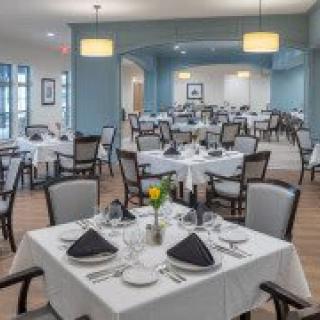 An elegant dining area set up with tables and chairs, each table adorned with formal place settings and decorative napkins.