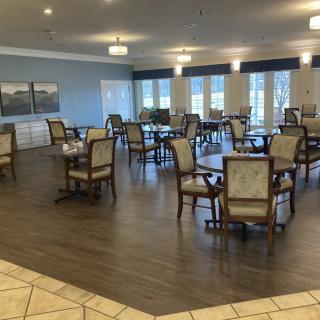 A spacious and well-lit dining room with multiple tables and chairs, featuring modern decor.