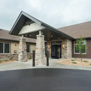 Entrance to a modern building with stone pillars and sloped roof.