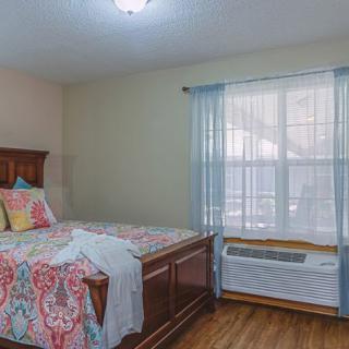 A cozy bedroom with a large window and colorful bedding.