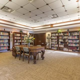 A cozy library reading area with shelves full of books and a central table with chairs.