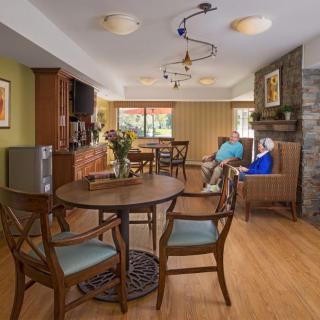 A cozy living room with wooden furniture, a stone fireplace, and colorful decor.
