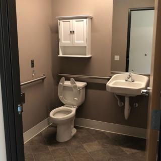A handicap-accessible bathroom with a toilet, sink, and wall cabinet.