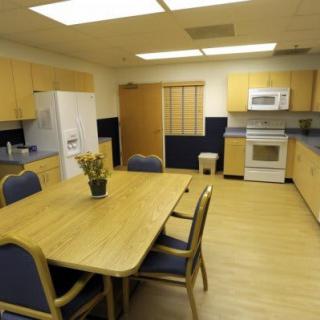 A modern kitchen and dining area with wooden cabinets, a table, and various appliances.