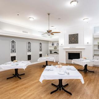 An elegantly decorated dining room with tables set with white tablecloths and a fireplace.
