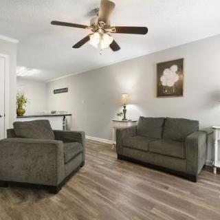 A cozy living room with two dark sofas, a ceiling fan, and wooden flooring.
