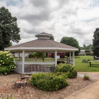A charming gazebo surrounded by lush greenery in a serene park setting.