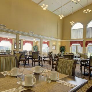 A spacious dining area with multiple tables and chairs, elegantly decorated with large windows and modern lighting.