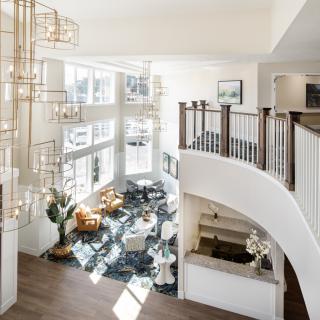 A modern living room with high ceilings, large windows, and a stylish staircase.