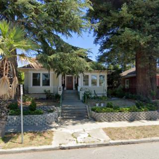 A house with a well-kept front yard and large trees in a residential neighborhood.