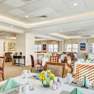 A spacious and elegantly decorated restaurant dining room with neatly arranged tables and chairs.