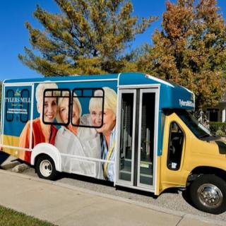 A brightly colored bus with an advertisement featuring seniors, parked on a sunny day.