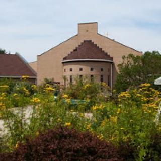 A scenic view of a unique architectural building surrounded by vibrant flowers in a garden.