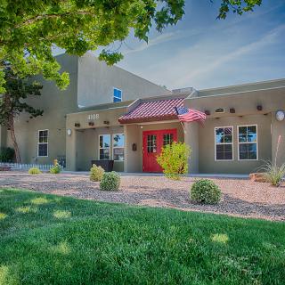 A modern house with a red door and well-maintained landscaping on a sunny day.