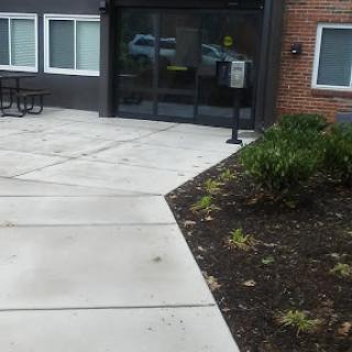 Entrance of a building with a sidewalk and landscaped area.