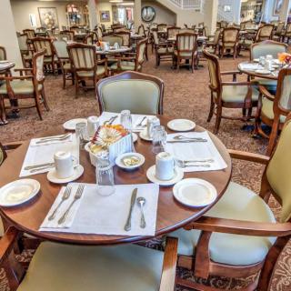 A neatly set table in a spacious dining area with multiple tables and chairs.