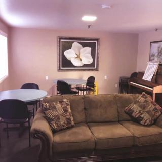 A cozy living room with a sofa, piano, and artwork on the wall.