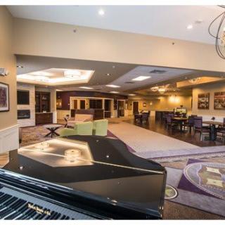 A modern and spacious lounge with a grand piano and dining area.