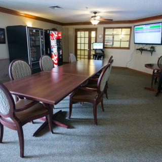 A spacious conference room featuring a long meeting table, comfortable chairs, and vending machines.