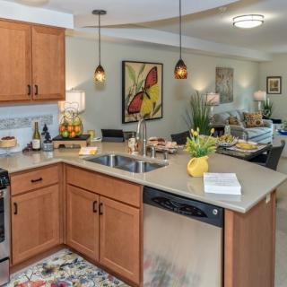 A modern kitchen with wood cabinets and an open concept layout leading to a cozy living room.
