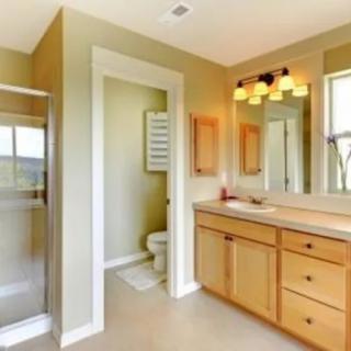 A modern bathroom featuring a wood vanity, large mirror, and a separate shower area.