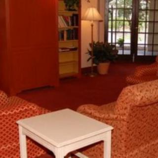 A cozy living room with armchairs, a small table, and a bookshelf.