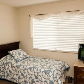 A cozy bedroom with a single bed and a small television by the window.