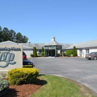 Front view of a building with a landscaped entrance and parking area.