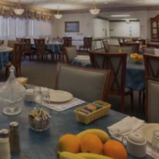 A spacious dining room with tables set for a meal, featuring fruit as a centerpiece.