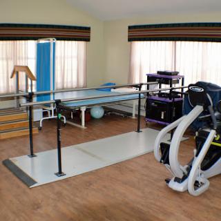 A well-equipped physical therapy room featuring a ballet bar, exercise mats, and various fitness equipment.