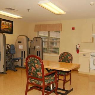 A small exercise room with chairs, a table, and exercise equipment.