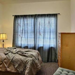 A cozy bedroom with a bed, lamp, and window curtains.