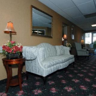 A cozy lobby area with a sofa, mirrors, and decorative lamps on side tables.