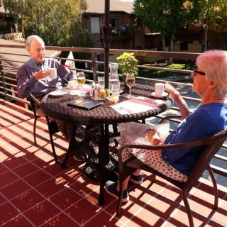 A couple enjoys a relaxing conversation over coffee on a sunny patio.