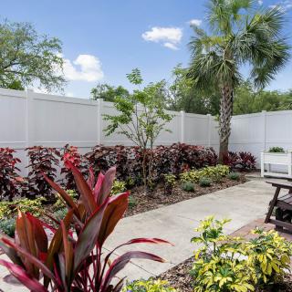 A well-maintained garden with a variety of plants and a white fence surrounding the area.