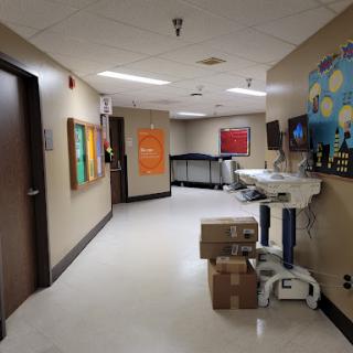 A view of a hospital hallway featuring colorful artwork and a medical cart.
