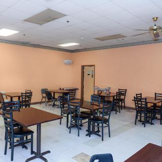 An empty restaurant dining area with rows of tables and chairs.