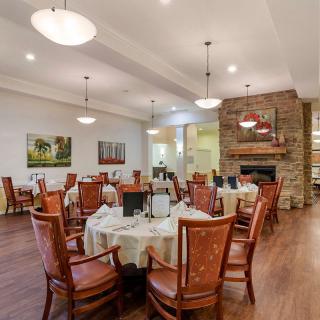 A cozy dining area featuring neatly arranged tables and chairs, with elegant lighting and a fireplace adding warmth to the ambiance.