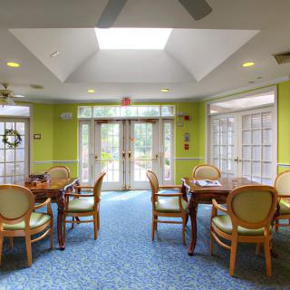 A bright dining area with tables and chairs, featuring large windows and a skylight.