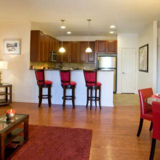 A modern open floor plan kitchen and living area with red accents and hardwood flooring.