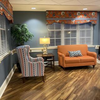 A cozy living room setup with an orange sofa, striped armchair, and warm lighting.