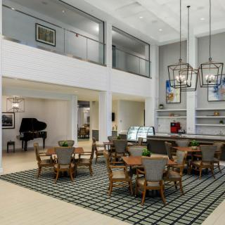 A spacious and modern interior dining area featuring elegant chandeliers, a piano, and stylish furniture.