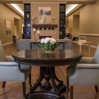 A cozy living room with elegant furniture and a central table adorned with flowers.