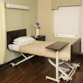 A neatly arranged hospital room with a single adjustable bed.