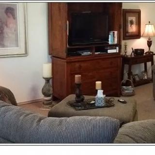 A cozy living room with a large TV stand, a comfortable couch, and decorative candles on the coffee table.