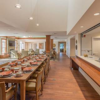 A spacious and modern dining room featuring a long table with an elegant table setting.
